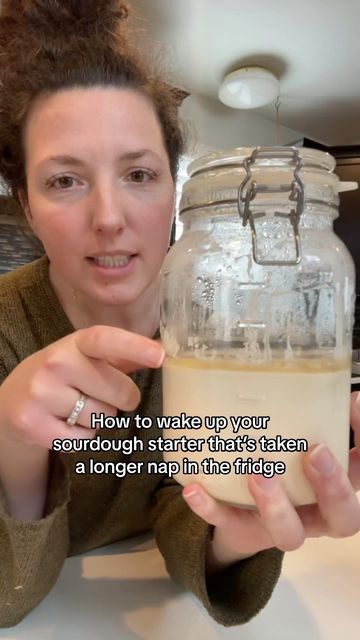 a woman is holding up a jar with something in it that says, how to wake up your sourdough star that's taken a longer nap than the fridge