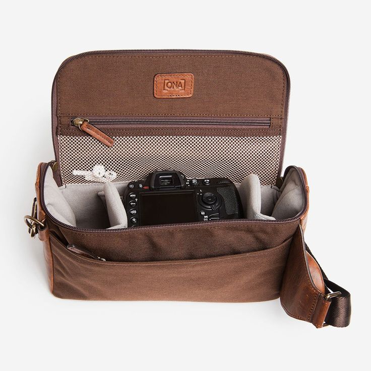 Store and easily access camera gear with the ONA Rockaway Camera Sling Antique Cognac Leather. A spacious main compartment features two padded, adjustable dividers to keep a DSLR and up to two lenses safe and secure, and a wide, removable shoulder strap is designed for maximum comfort. Three additional zippered pockets provide storage for accessories or personal items. Crafted from premium leather and solid brass hardware, this heirloom-quality sling is both stylish and sturdy. Exterior Dimensio Rectangular Camera Bag For Outdoor Use, Rectangular Camera Bag For Outdoor, Brown Travel Camera Bag With Adjustable Strap, Outdoor Camera Bag With Rectangular Shape, Brown Camera Bag With Adjustable Strap For Travel, Outdoor Leather Camera Bag With Adjustable Strap, Leather Camera Bag With Adjustable Strap For Outdoor, Functional Leather Camera Bag, Brown Functional Rectangular Camera Bag