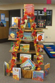 a library filled with lots of books on top of a wooden book shelf covered in fall leaves