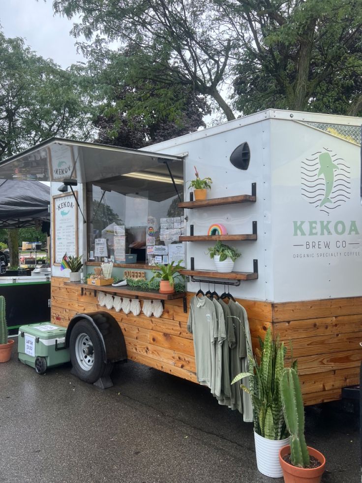 a food truck is parked on the side of the road with potted plants in it