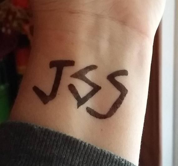 a person with a tattoo on their wrist that has the letters j and s written in black ink