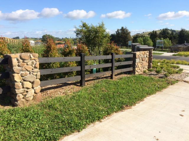 a stone and wood fence on the side of a road