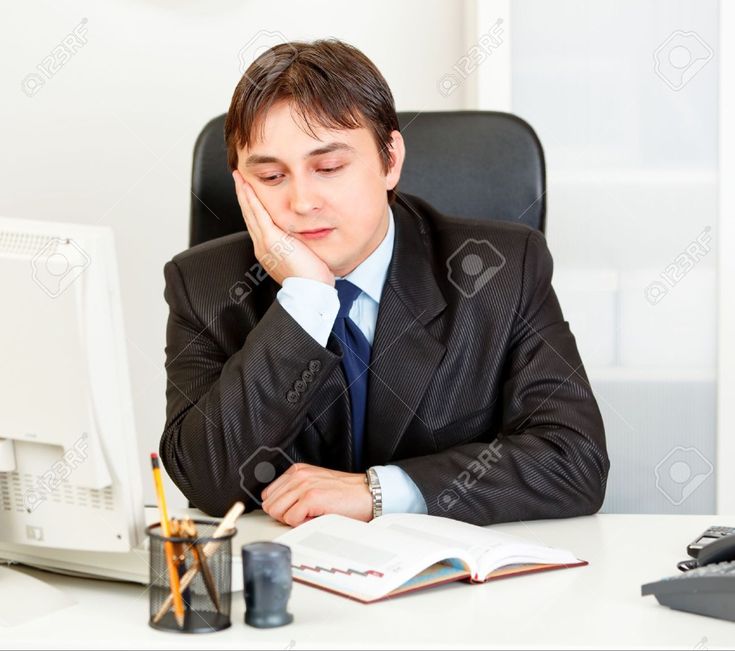 a man sitting at a desk in front of a computer with his hand on his face