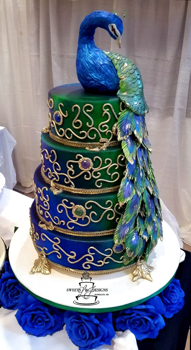 a peacock sitting on top of a multi tiered cake