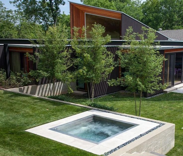 an outdoor hot tub in the middle of a yard with grass and trees around it