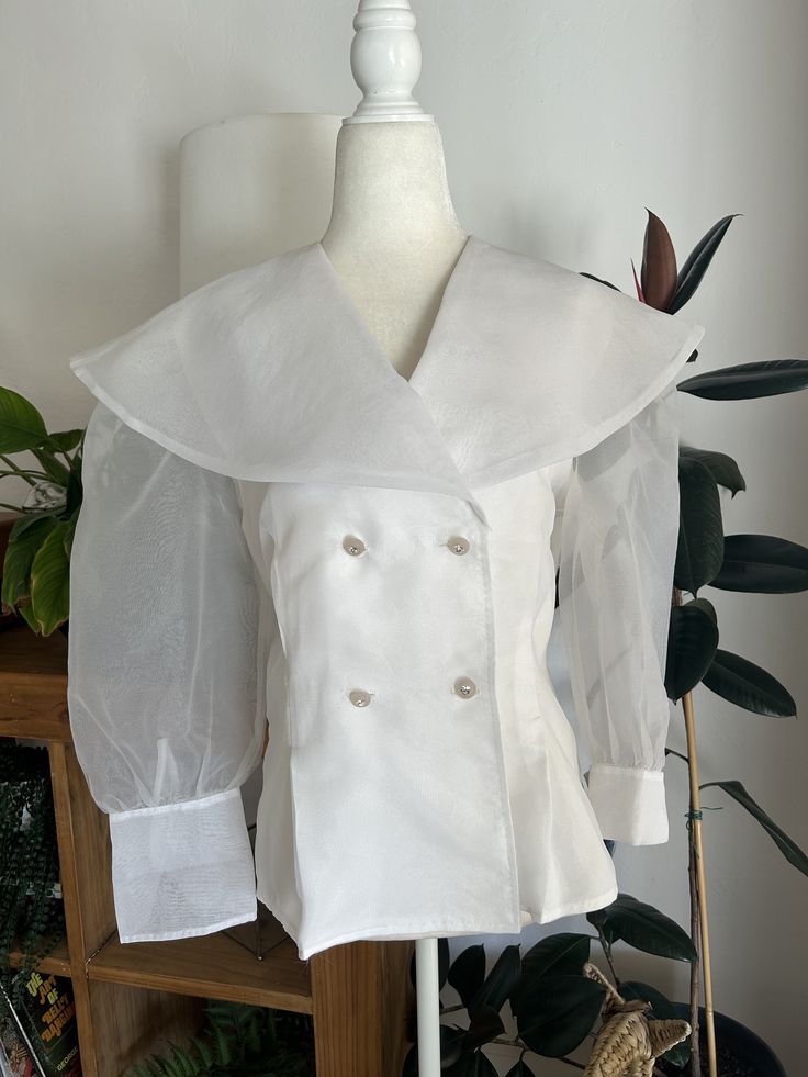 Make a statement in this stunning, white, chiffon, double breasted blouse. Blouse is double lined so that it is less sheer and buttons down the front and at the wrist with jeweled buttons. In overall great vintage condition with no notable flaws, no holes, snags, stains, etc. Label reads Bonnie and Norma, size 10.  Measurements Chest 40in/101.5cm Waist 34in/86.5cm Length 27in/68.5cm Shoulder 16.5in/42cm Sleeve 19.5in/49.5cm *Please keep in mind that unless otherwise noted, all items in my shop a Spring Organza Tops For Workwear, Elegant Organza Blouse For Office, Elegant Button-up Tops With Sheer Sleeves, Long Sleeve Organza Tops For Work, Elegant Party Tops With Covered Buttons, Sheer Organza Tops For Workwear, White Sheer Button-up Blouse, Classic Fitted Blouse With Sheer Sleeves, Classic Blouse With Sheer Sleeves And Fitted Design