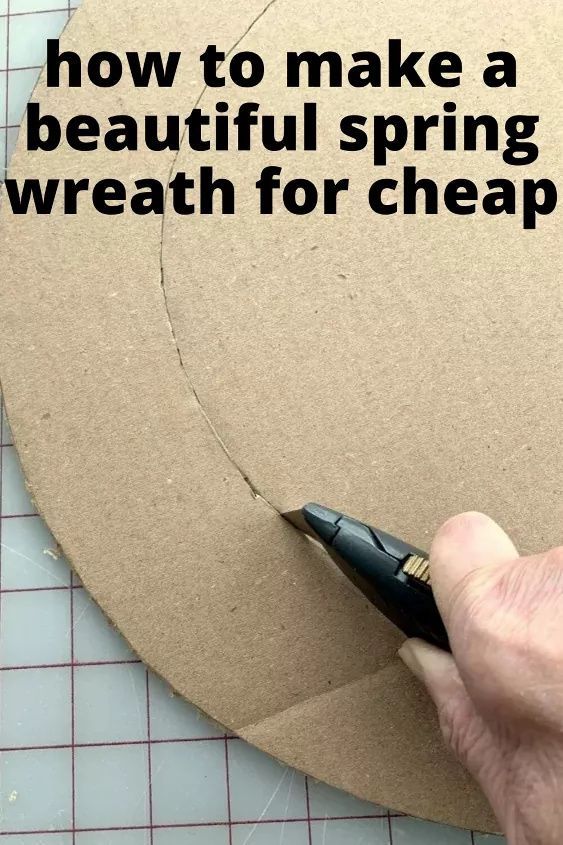 a person cutting out a piece of cardboard with a sharpie pen on it and the words how to make a beautiful spring wreath for cheap