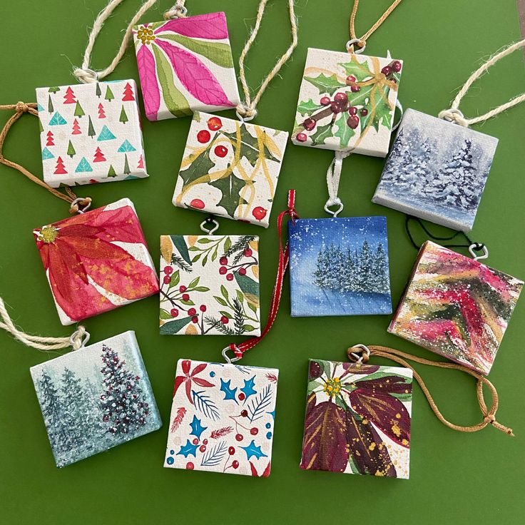 small christmas cards are hanging from twine strings on a green surface with red, white and blue decorations