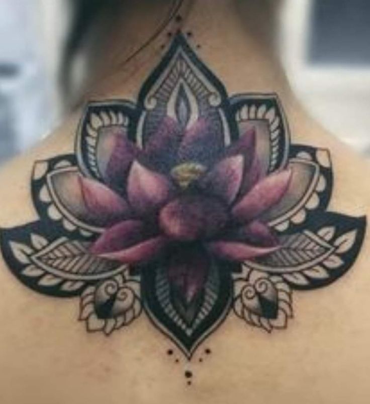 the back of a woman's neck with a lotus tattoo on it