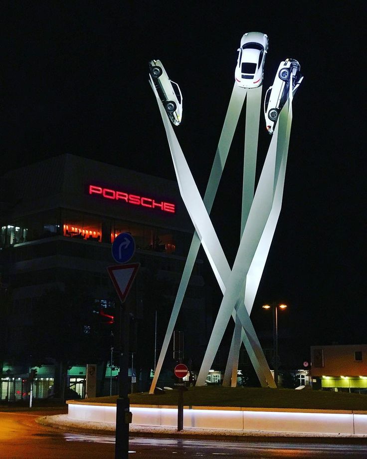 two cars are on display in front of a porsche dealership at night with the lights turned on