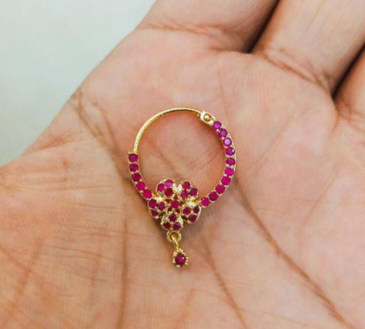 a gold ring with pink and red stones in the shape of an elephant's head