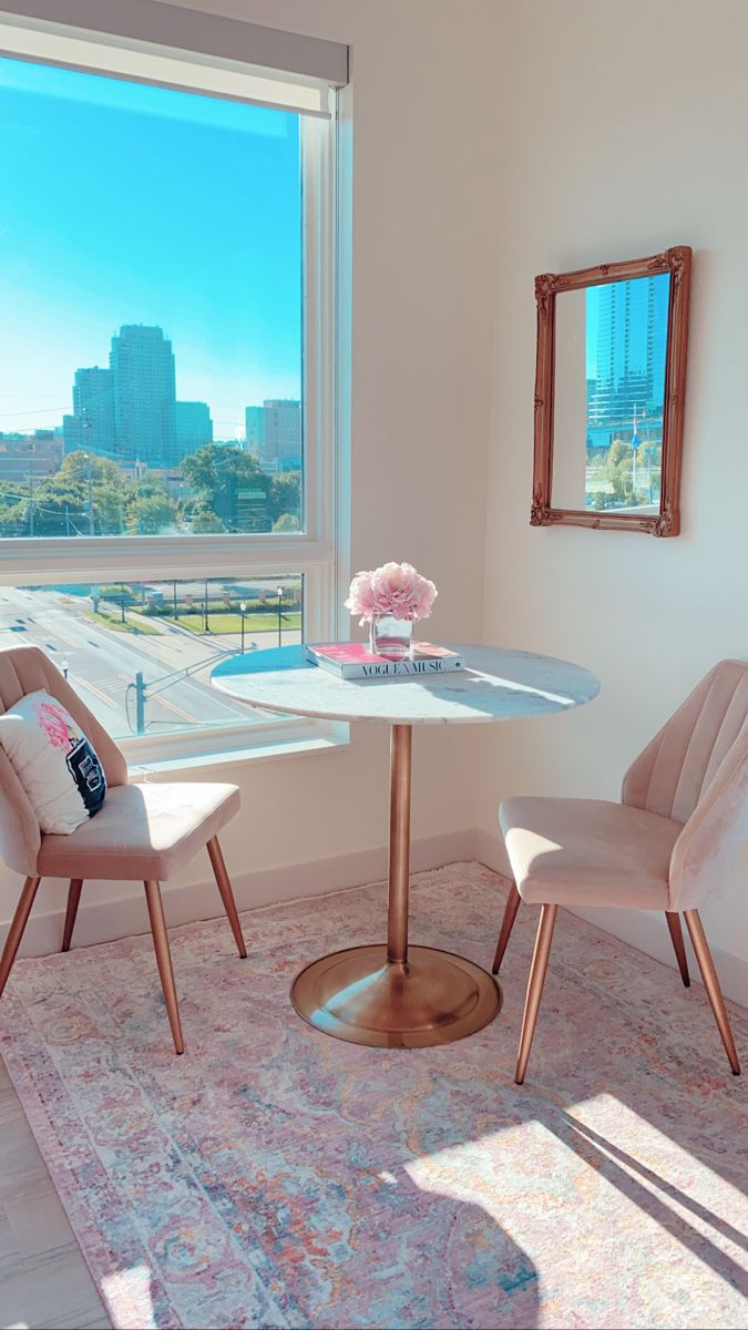 two chairs and a table in front of a large window with city view on the other side