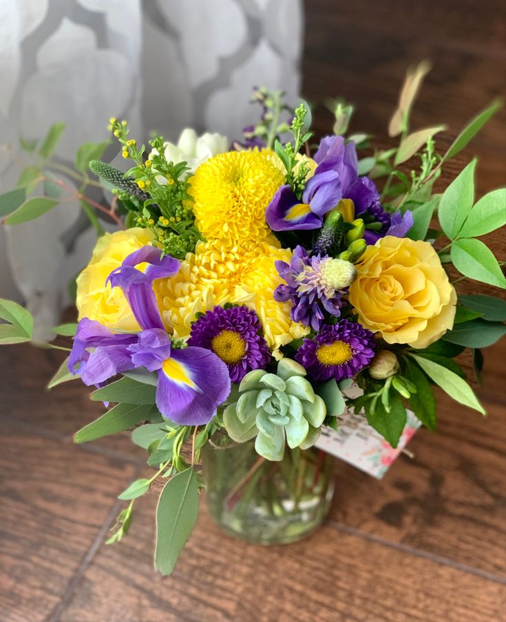 a vase filled with yellow and purple flowers