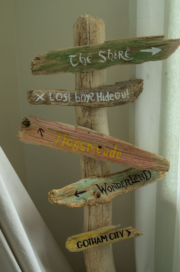 a wooden sign with many different signs on it's sides pointing in different directions