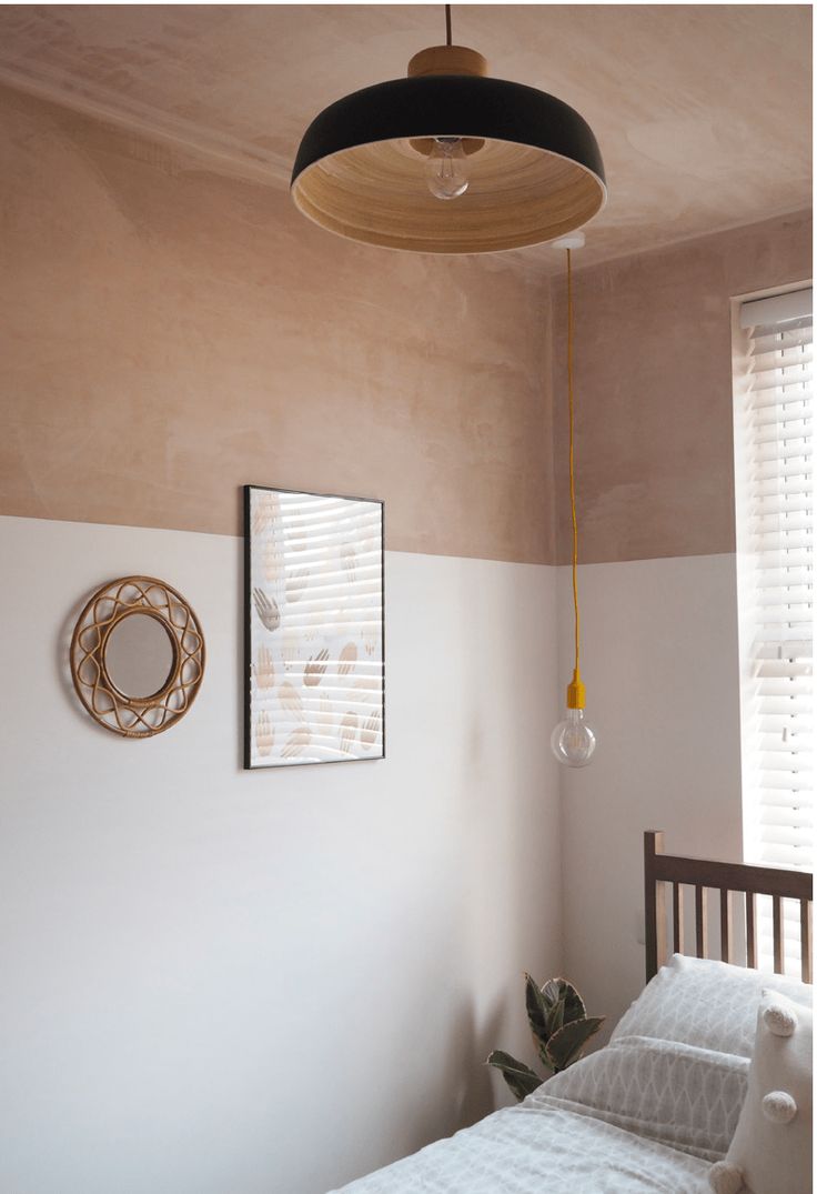 a bedroom with a bed, lamp and pictures hanging on the wall next to it