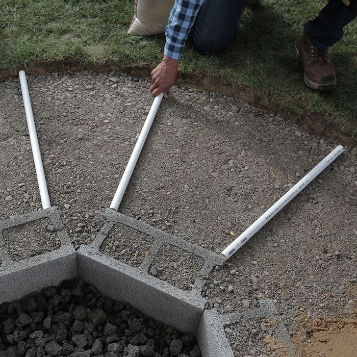 a man kneeling down next to a hole in the ground