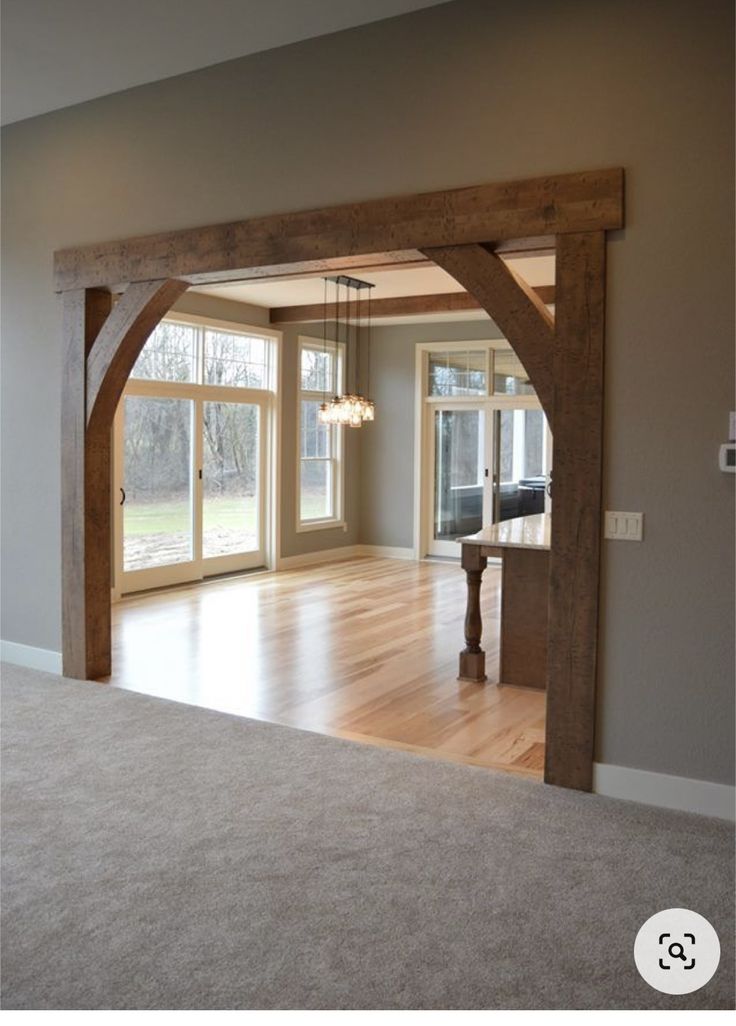 an empty living room with large windows and wooden beams