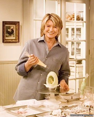 a woman standing in front of a counter holding a brush and bowl with food on it