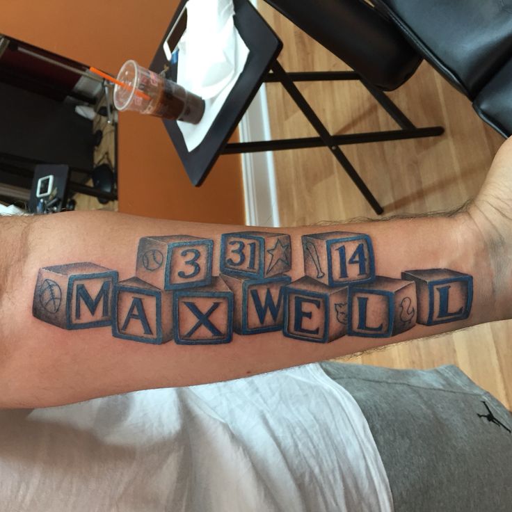 a man's arm with the word maxwell written in blocks and numbers on it