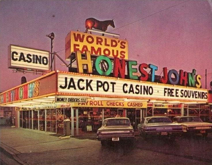 an old photo of a casino with cars parked in front and neon signs on the building