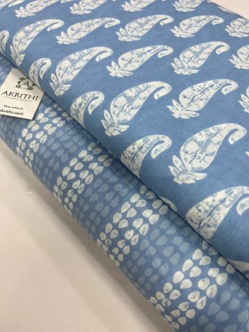 two pieces of blue fabric with white designs on them, one is folded and the other has