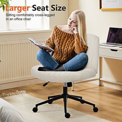 a woman sitting in an office chair with her feet on the desk while reading a book