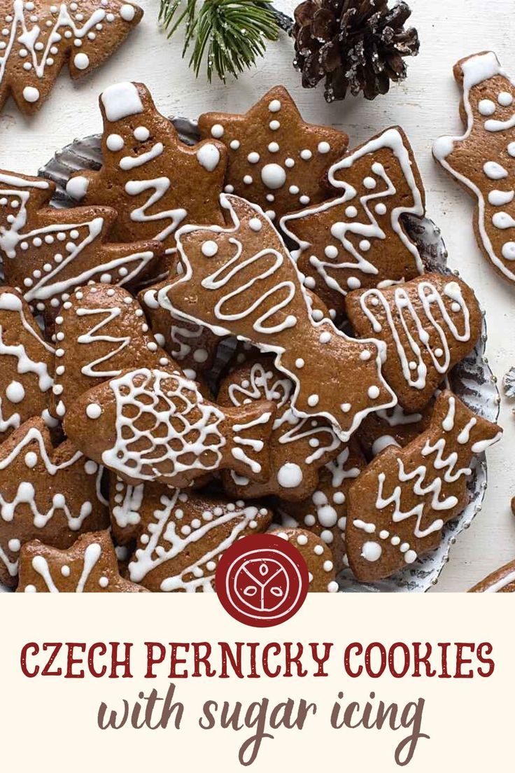 a plate full of cookies with white icing on them and pine cones in the background