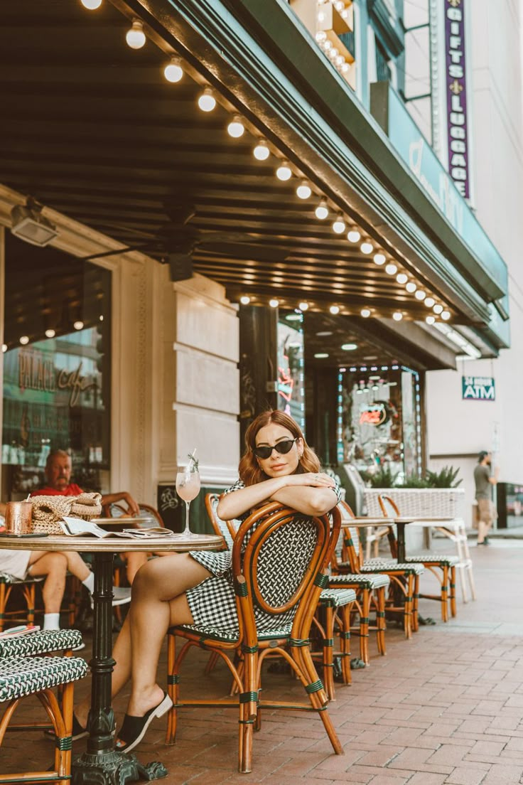 a woman sitting at a table in front of a restaurant with her arms crossed and legs crossed