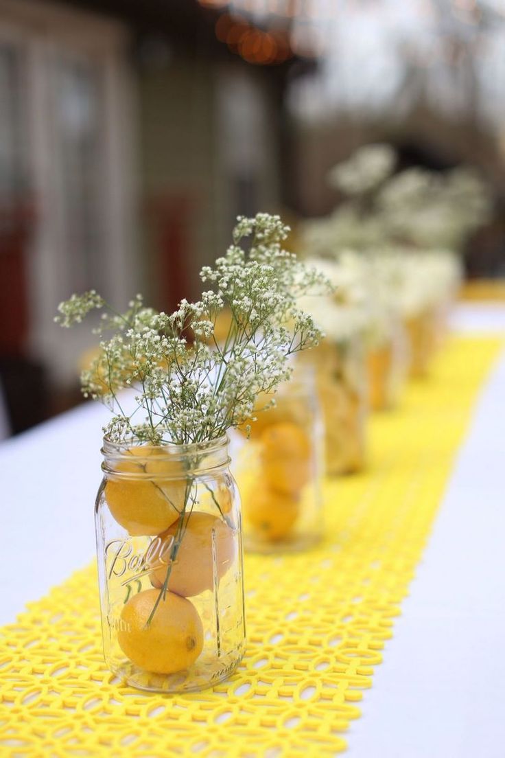 several jars filled with lemons and baby's breath on a yellow table cloth