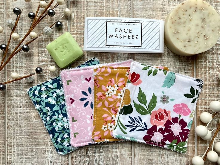 four different floral fabric squares next to some soaps and flowers on a wooden table