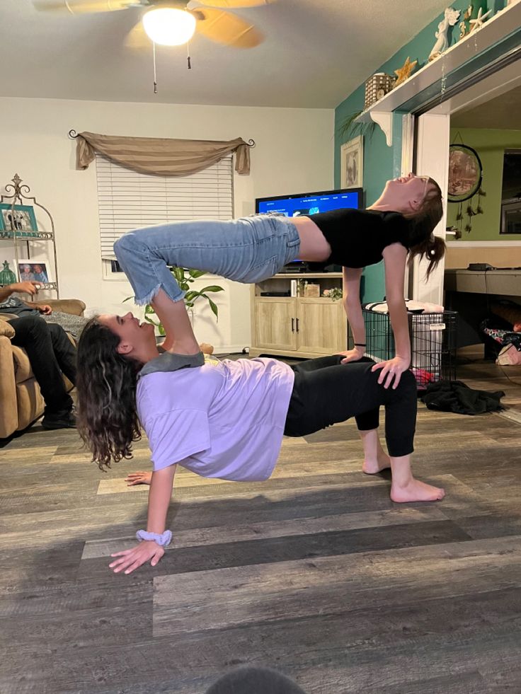 two women doing yoga poses in front of a flat screen tv on the living room floor