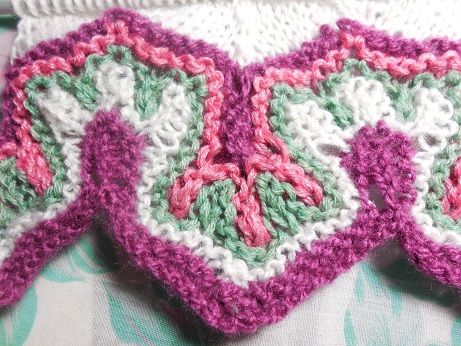 two crocheted dishcloths sitting on top of a bed next to each other