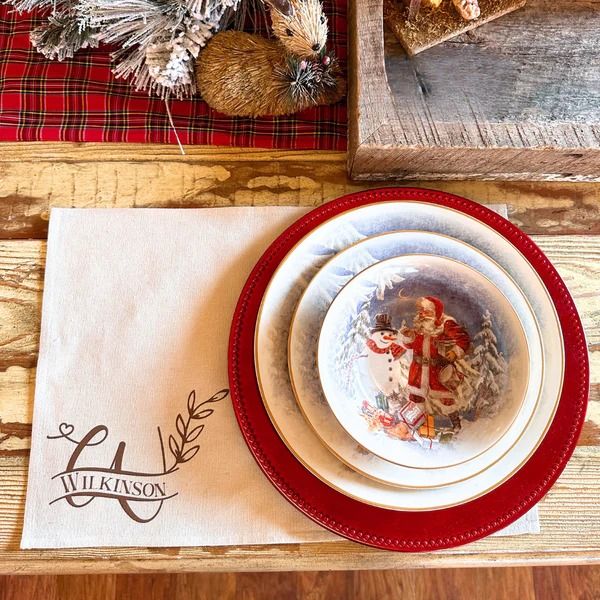 a table with plates, napkins and other items on it in front of a christmas tree