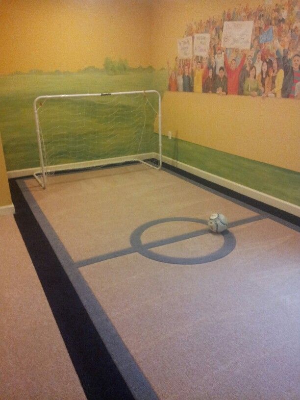 a soccer goal in the corner of a room with a mural on the wall behind it