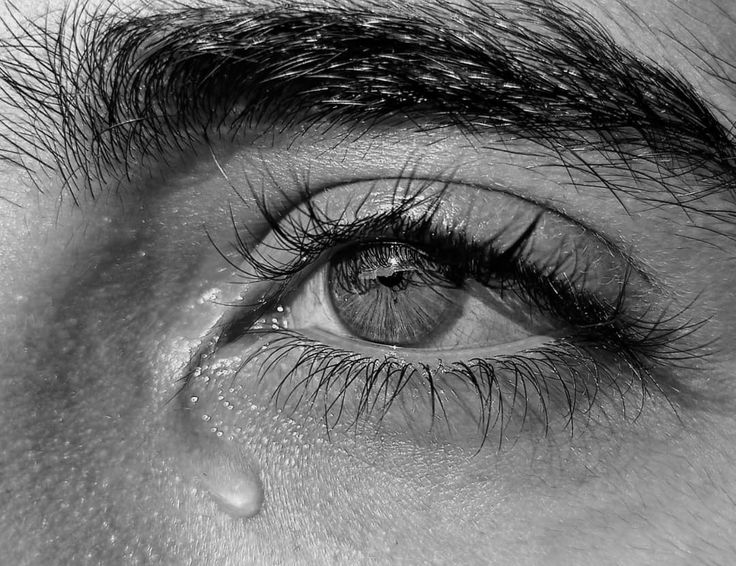 the eye of a man with teary eyes and long eyelashes, black and white photo