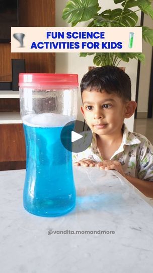 a young boy sitting at a table in front of a blue cup filled with liquid