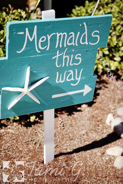 a wooden sign that says mermaids this way with an arrow pointing to the right