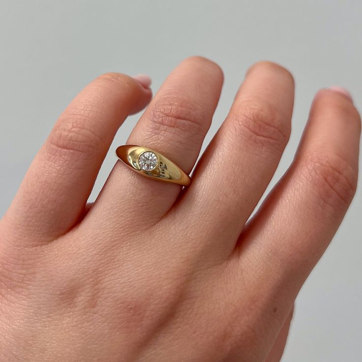 a person's hand with a gold ring on it and a diamond in the middle