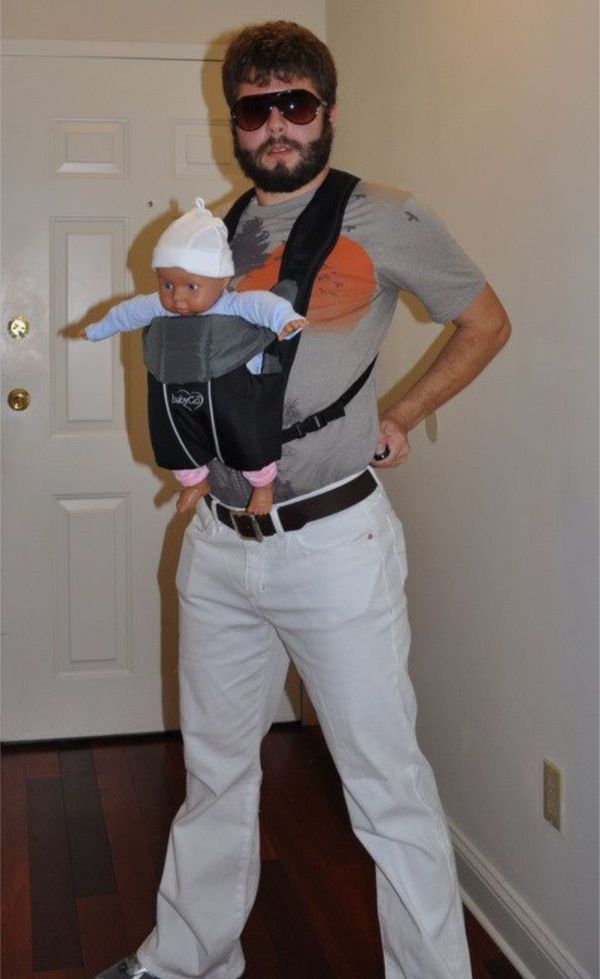 a man holding a baby in his arms while standing on a hard wood floor next to a door