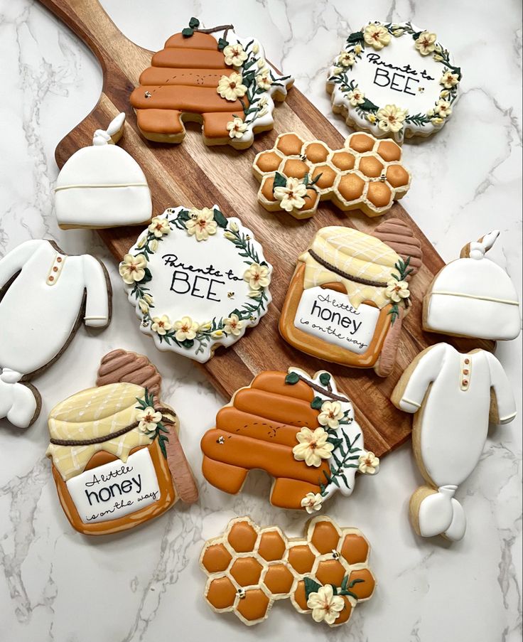 decorated cookies on a wooden cutting board with honey and bee decorations in the shape of cutouts