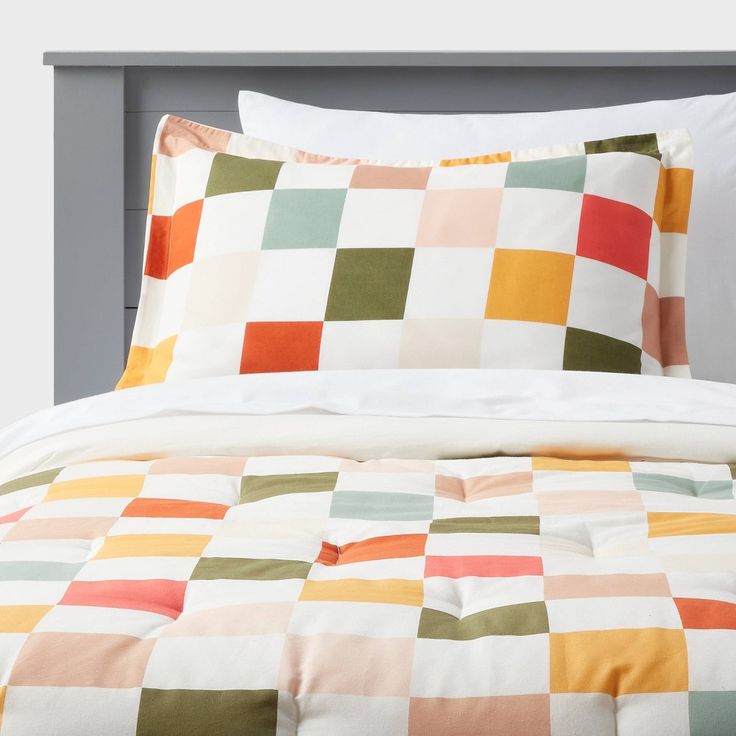 an image of a bed setting with colorful squares on the comforter and pillow cases