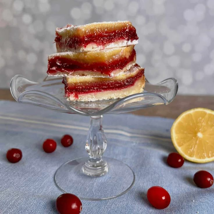 three pieces of cake sitting on top of a glass plate with cherries around it