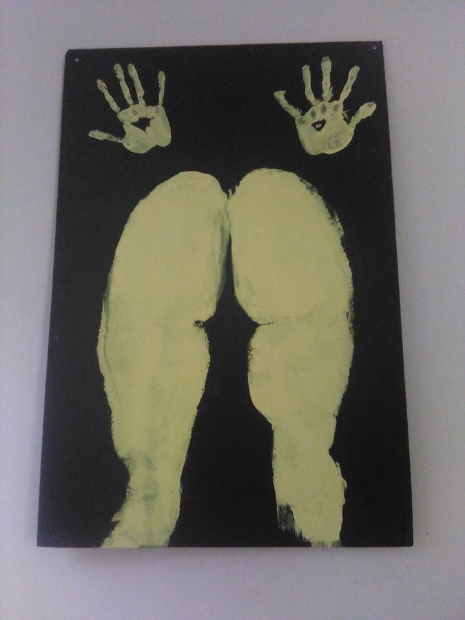 an image of two hand prints on a black and yellow paper with white paint in the middle