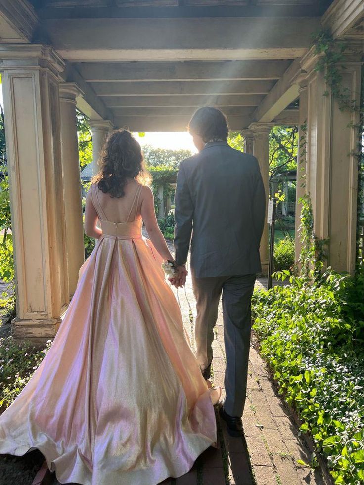 a man and woman walking down a walkway holding hands