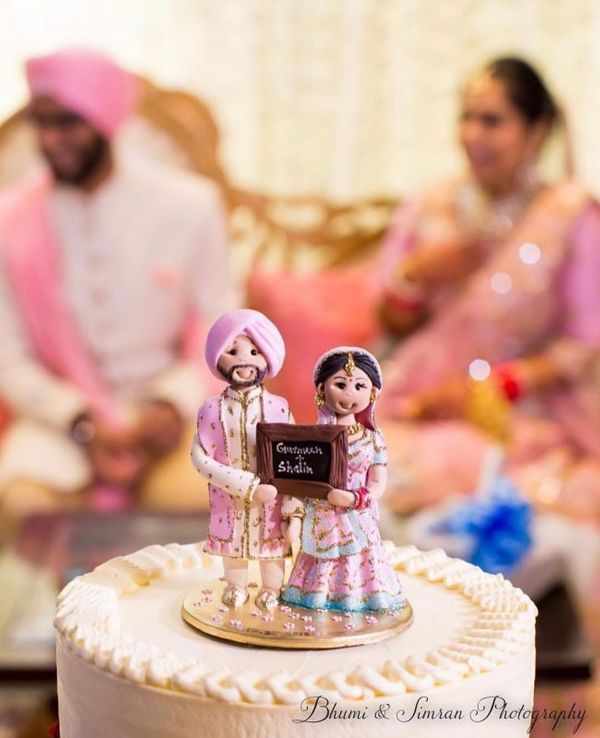 a cake with two figurines on top of it and people in the background