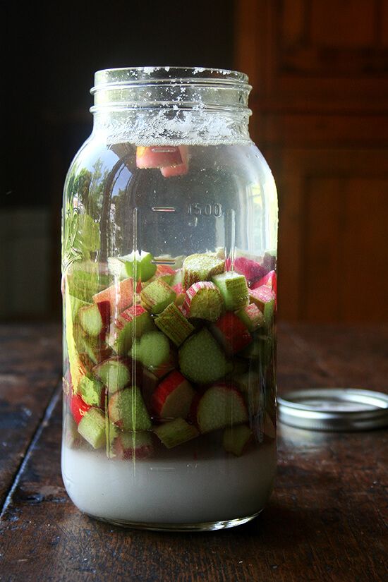 a jar filled with lots of fruit sitting on top of a wooden table