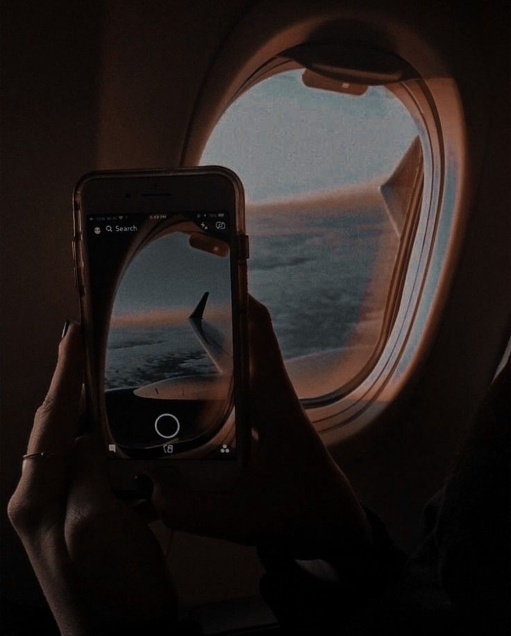 a person taking a photo of an airplane window with their cell phone in front of them