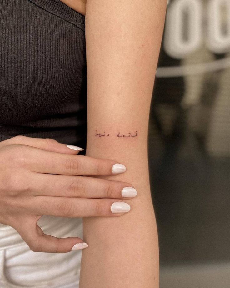 a woman's arm with a small tattoo on the left side of her wrist