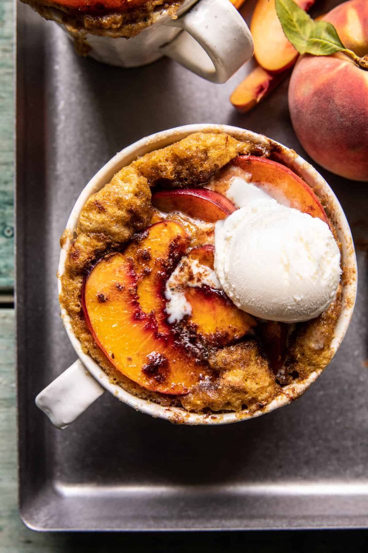 two mugs filled with ice cream and peaches on a tray next to each other