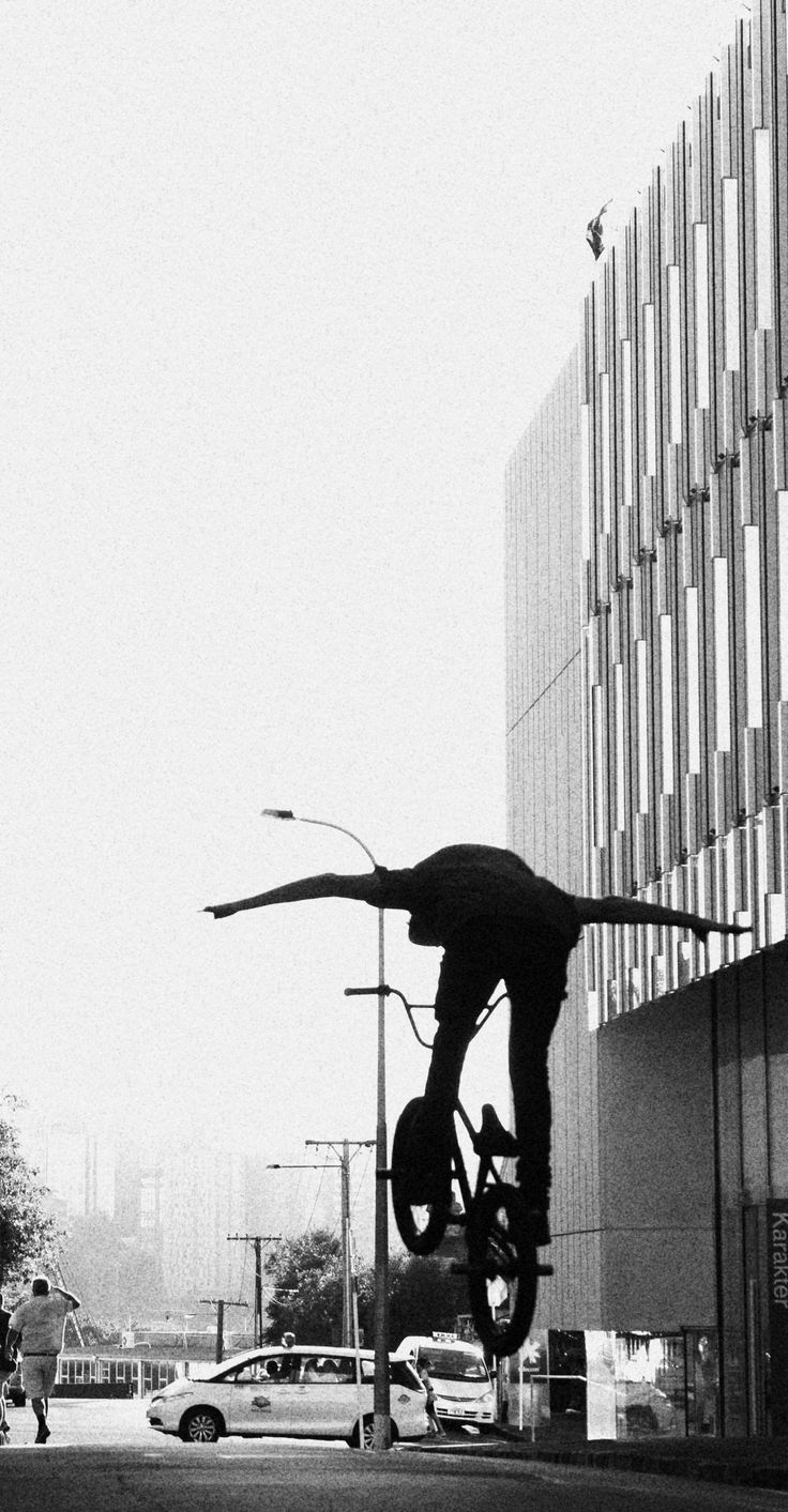 a skateboarder is doing a trick in the air near a building and cars